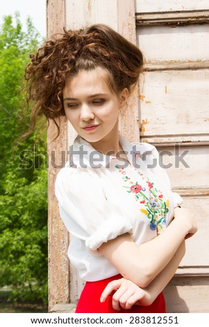 A girl in a white shirt embroidered on the front porch of an old wooden house