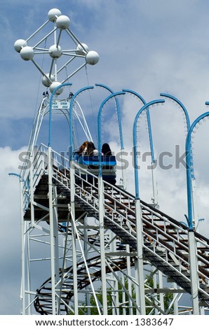 A car of riders reaches the top of an old roller coaster ride