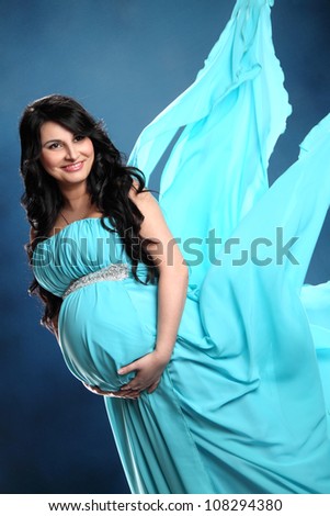 beautiful pregnant woman in a blue dress in the wind