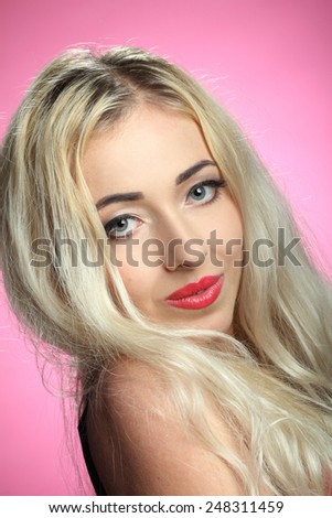 portrait of a beautiful woman on a pink background. blonde, beautiful, long hair. good makeup. sexy look