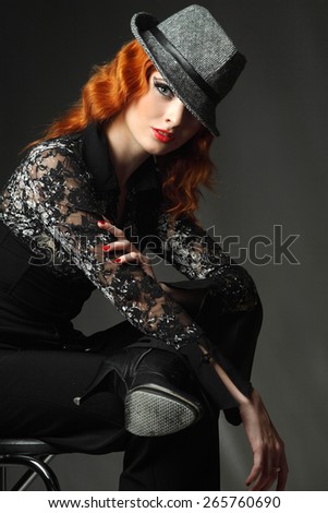 Portrait redhead, a young woman in hat. against a dark background. sexy look, lush red lips. fashion evening make-up. artistic hand gestures