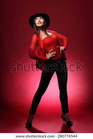 beautiful woman in a hat on a red background. flirty look. Game emotions. beautiful figure