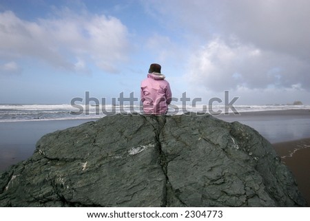 Pink woman on rock by ocean