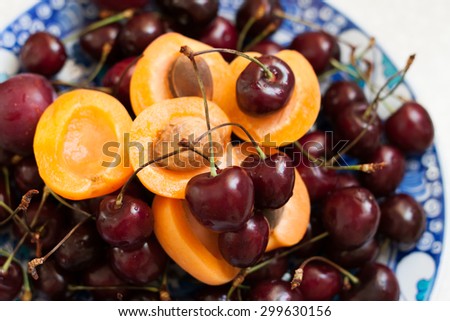 juicy cherries and apricots on bright beautiful plate with oriental motifs