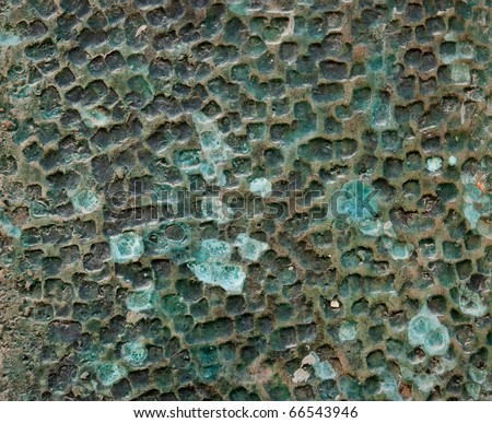 The rough relief of a wall covered with green and blue glaze