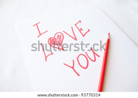 The declaration of love written on a clean sheet of a paper by a red bright pencil