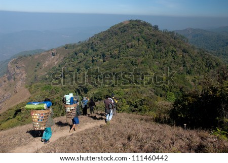 Group of peoples carries heavy load during  trekking on high mountain in Northern of Thailand.