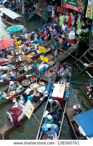 SAMUTSONGKRAM,THAILAND- JULY 27 : Wooden boats busy ferrying people at Amphawa floating market on July 27,2012. Traditional popular method of buying and selling still practiced in canals , Thailand.