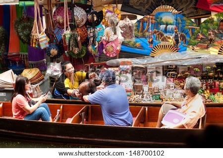 RATCHABURI,THAILAND -JULY 21 : Tourist buying souvenir from local merchant at Damnoen Saduak floating market,on July 21,2013 in Ratchaburi,Thailand .Dumnoen Saduak is a very popular tourist attraction.