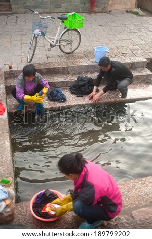LIJIANG,CHINA Ã¢Â?Â? MARCH 17 : The daily lives of Naxi woman washing on ancient pool is White horse Dragon at Dayan old town on March 17, 2014 in  Lijiang city,Yunnan province,Southwestern of China.