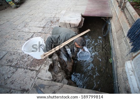 LIJIANG,CHINA Ã¢Â?Â? MARCH 15 : The daily lives of Naxi Chinese male used to draw water  at Dayan old town on March 15, 2014 in  Lijiang city,Yunnan province,Southwestern of China.