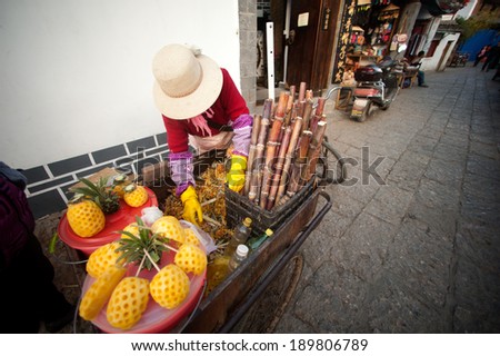 Lijiang,China Ã¢Â?Â? March 15 : Chinese woman at a Rickshaw loaded with fruit in Lijiang is the largest ancient old town on March 15, 2014 in China,Lijiang city,Yunnan province in Southwestern of China.