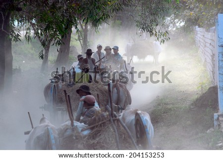 BAGO,MYANMAR-JANUARY 31 : Group of unidentified farmer riding on their ox cart, carrying supplies the route runs along to a village on January 31,2014 in Bago city,Middle of Myanmar.