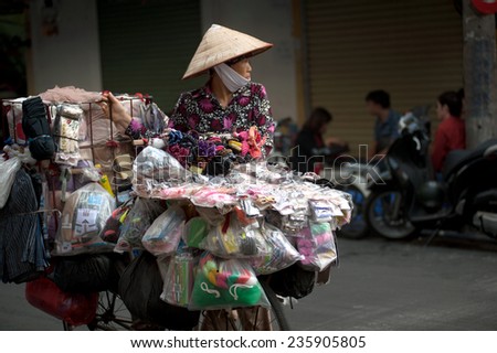 HANOI,VIETNAM-OCT 12 : Daily life of the appliance vendors sell on her bicycle in the typical street in old town on October 12,2014 at Hanoi city,Vietnam.This is small market for retails and hawkers.