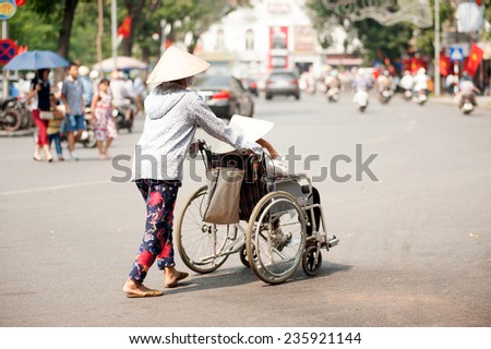 HANOI,VIETNAM - OCTOBER 12 : Vietnamese patient with a wheelchair for exercise and relax common in the street on October 12,2014 in Hanoi city,Vietnam.
