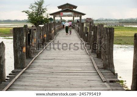 AMARAPURA,MYANMAR-JUN 30: Unidentified local citizens crossing U-Bein Bridge located on Taungthaman lake.Bridge is believed to be the oldest teak bridge in the World on June 30,2014,Amarapura,Myanmar.