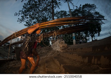 MANDALAY,MYANMAR-JULY 2 : Daily life of Worker carrying bamboo on Port activities in Ayeyarwaddy river for sell on July 2,2014 in Mandalay city, Central of Myanmar.