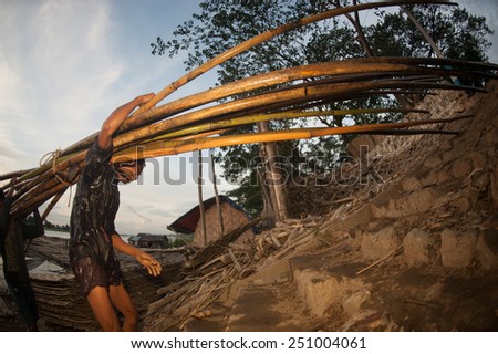 MANDALAY,MYANMAR-JULY 2 : Daily life of Worker carrying bamboo on Port activities in Ayeyarwaddy river for sell on July 2,2014 in Mandalay city, Central of Myanmar.