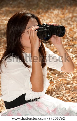 Pretty Asian woman sitting ground seeking binoculars .