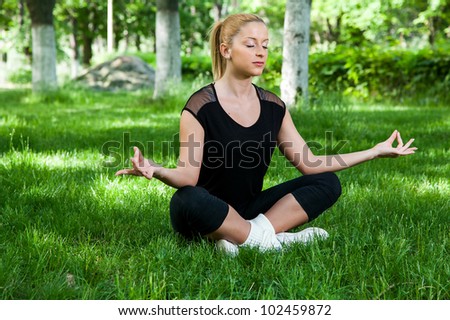 Beautiful teenage girl making yoga in the park in spring