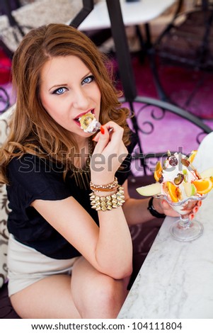 beautiful girl eating an ice cream with fresh fruits outside