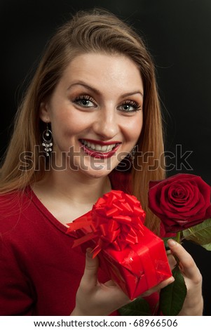Beautiful girl with rose holding a red gift