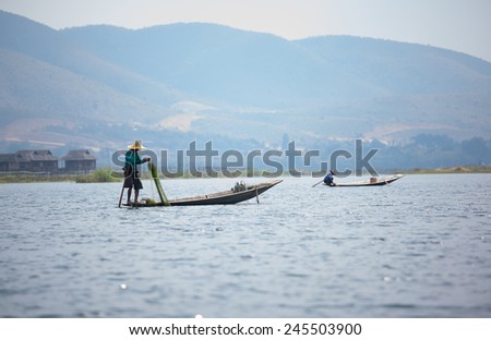 INLE LAKE, MYANMAR - FEBRUARY 15: Unidentified man rowing a wooden boat in Inle Lake with its leg-rowing and fishing. Intha people is a major tourist destination on Feb 15, 2014 in Inle lake, Myanmar.