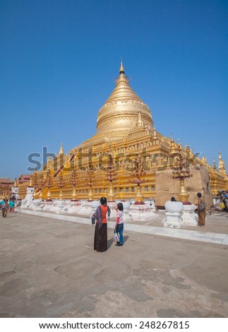 BAGAN, MYANMAR - MAR 04: Unidentified peoples visit Shwezigon Pagoda, It\'s a prototype of Burmese stupas and consists of a circular gold leaf-gilded stupa surrounded by smaller temples on Mar 04, 2012