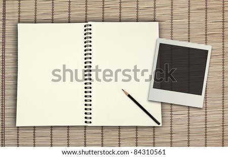blank book with pencil and photo frame on bamboo plate