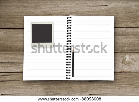 blank book with pencil and photo frame on the wooden background