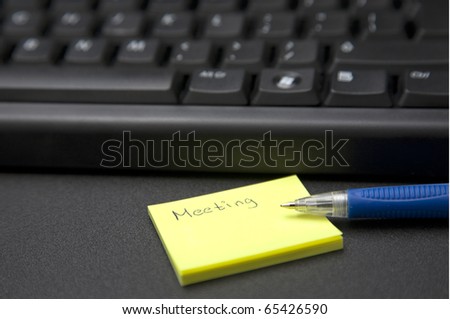 Close up shot of a post it with the word meeting written on it