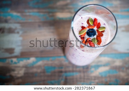 Healthy fruit smoothie milkshake of Kefir yogurt and pineapple topped with goji berries, pumkin seeds and a blueberry.