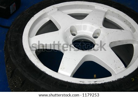 Used white aluminium rally racing wheel put to the ground.