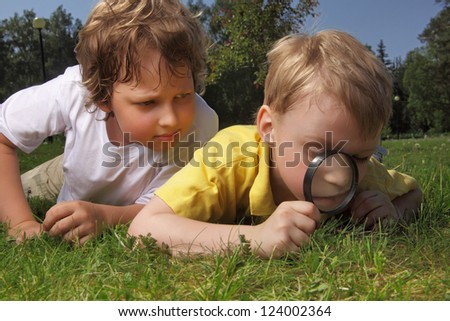 two boys with magnifying glass outdoors