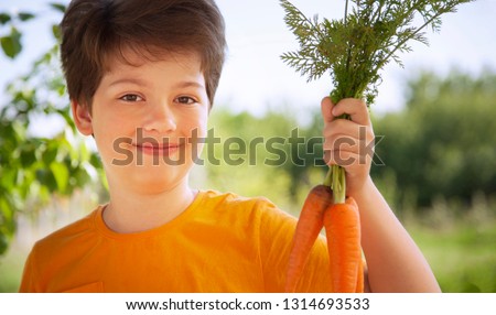 Happy boy biting the carrot, A child with a vegetable. Kid eating fresh carrots