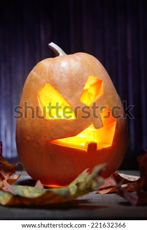 Jack o lanterns  Halloween pumpkin face on wooden background and autumn leafs