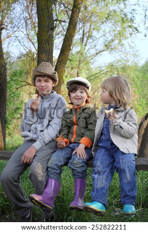 3 boys on the forest bench eat bun