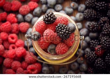 different berries (blueberries raspberries blackberries) in a basket on a wooden table