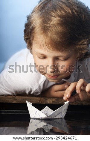 boy play in paper ship in water puddel