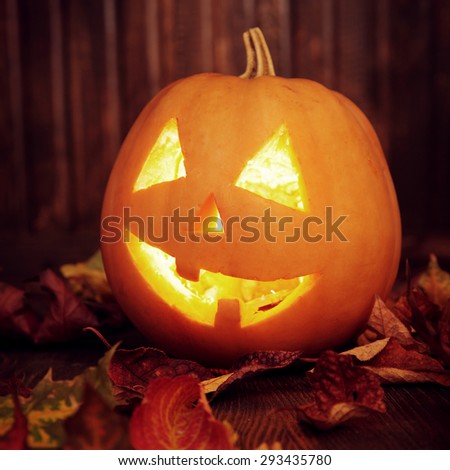 Jack o lanterns  Halloween pumpkin face on wooden background and autumn leafs