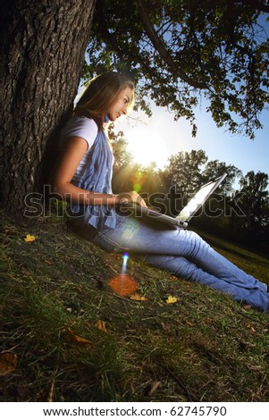 young beauty girl with laptop in park, photo with artistic lens flare effect