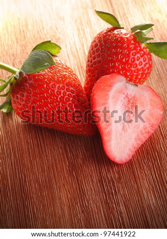three strawberries on  wood deck