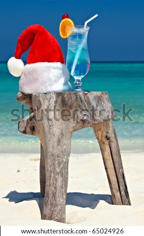 Bocal of tonic water is on original  beach table is made from trunk of tree with Santa hat
