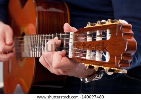 Brown guitar in hands of the guy playing it