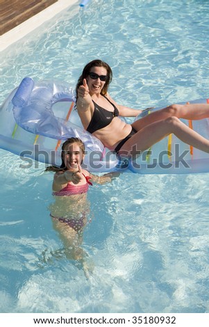 mother and daughter playing in a swimming pool with a inflatable bed