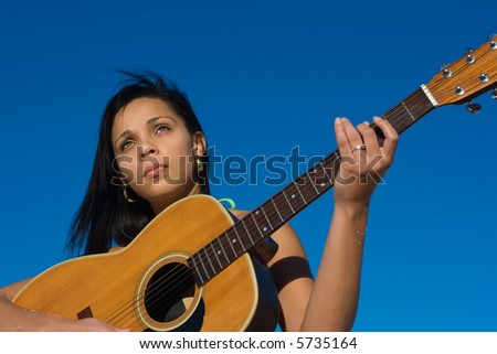 Ethnic female guitarist with blue sky background