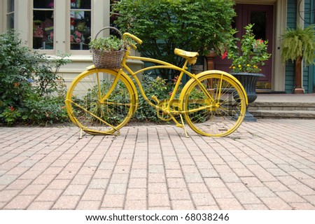 Decorative yellow bicycle resting on a sidewalk