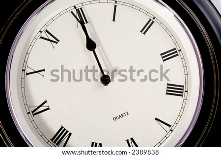 Circular clock with Roman numerals showing twelve o\'clock (12:00).