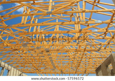 Roof trusses sitting a cement block walls view from inside home. Blue sky with clouds in background