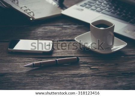 vintage composition of modern wooden table desk with smartphone laptop and cup of coffee